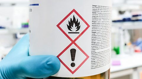 Bottle containing a dangerous, toxic substance with appropriate safety signs visible on a label.