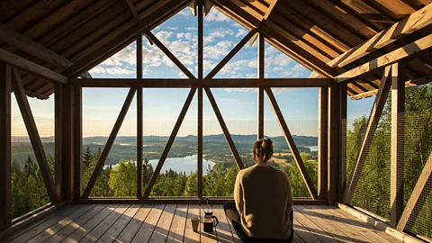 Martin Edström A woman sat on a decking looking out to a view of a lake and greenery (Credit: Martin Edström)