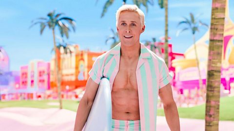 Ken from Barbie movie holding a surfboard in a tropical beach setting, wearing a pastel-striped outfit with open shirt; surrounded by palm trees and vibrant, colorful buildings