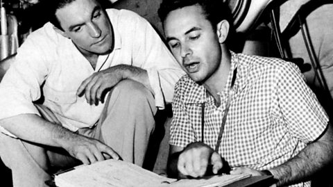 Gene Kelly and Stanley Donen rehearsing for 'Singin' in the Rain,' seated and reviewing a large open binder; a candid moment of collaboration between the film’s co-directors during musical preparations