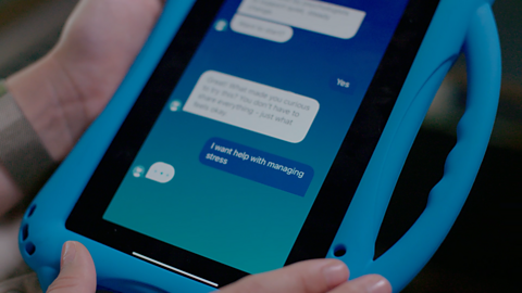 Anya holding a tablet with the Wysa wellbeing chatbot on screen