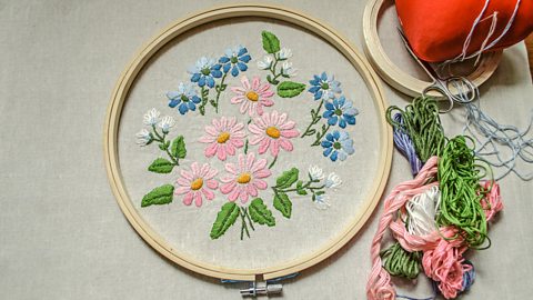 Obair-ghrèis de fhlùraichean pinc, gorm is geal, frèam fiodha, snàthainnean dathte, snàthad is siosar