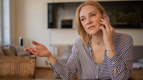 Mum sat on dining table talking on the phone 