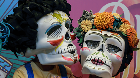 Two Day of the Dead skull masks with colourful patterns and flowers