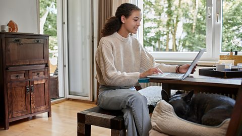 A teenage girl works on her laptop at home