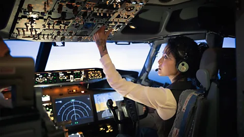 Getty Images Female pilot adjusting switches on the control panel while sitting inside cockpit (Credit: Getty Images)