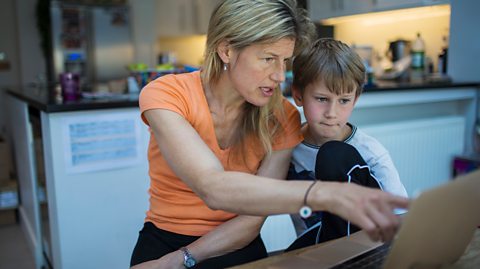 A mother and son looking at a laptop
