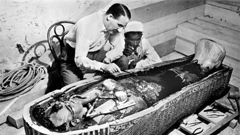 A photo of Howard Carter investigating Tutankhamun's sarcophagus.