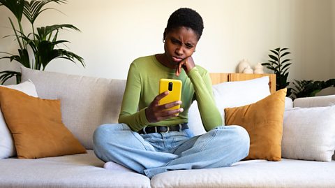 An image showing a young woman looking at her smartphone with a concerned expression