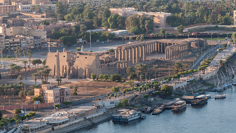A photo of the ruins of the Temple of Luxor next to the River Nile.