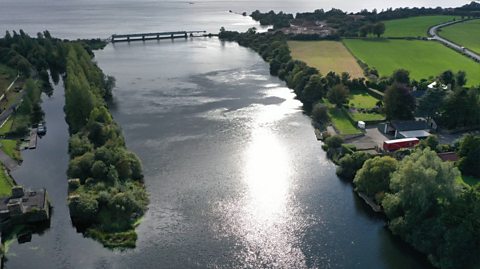 An aerial view of Lough Neagh, the UK's largest freshwater lake. Here, you can see the sun beaming off the water and green land on both sides 