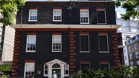 A shot of a red brick house in Mayfair, London. The left hand side of the house has five large windows and a front door. On the right hand side, five of the six large windows are bricked up