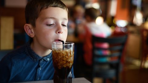 small boy drinks coca-cola through a straw