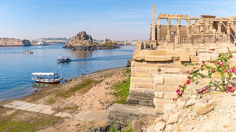 A photo of the River Nile with the Philae temple complex in the foreground.