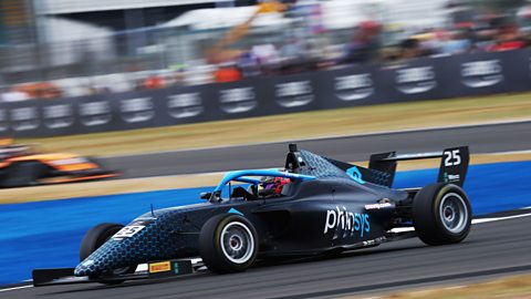 A navy blue Formula 4 car with light blue trim races from right to left. It has the number 25 on the rear spoiler