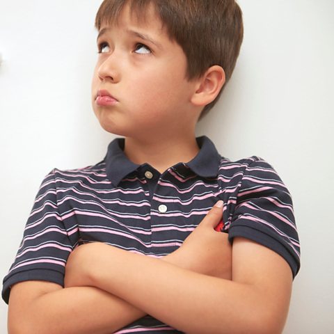 young boy looks defiant when being asked to apologise by a parent
