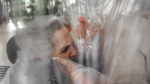 Max Cavallari People hugging through a plastic sheet in room in Italian care home in November 2020 (Credit: Max Cavallari)