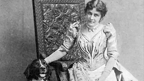 Vintage black-and-white portrait of Eunice Newton Foote in an ornate Victorian-style gown seated beside a dog, with a decorative carved panel in the background.