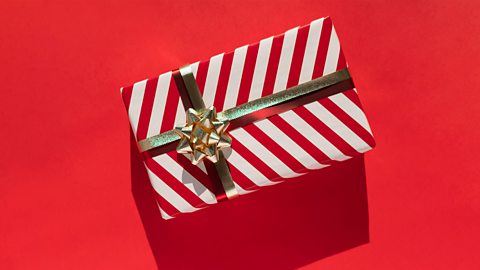 A square red gift box with brown ribbon wrapped around it