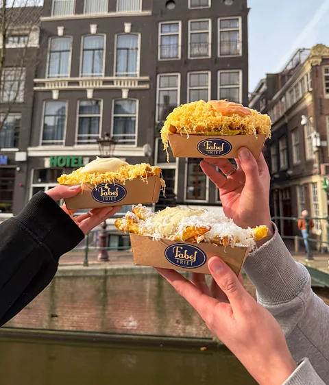 FabelFriet Close up of three hands holding cartons of fries with Fabelfriet label on them (Credit: FabelFriet)