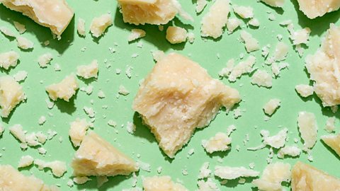 Broken up pieces of Parmesan on a pale green background