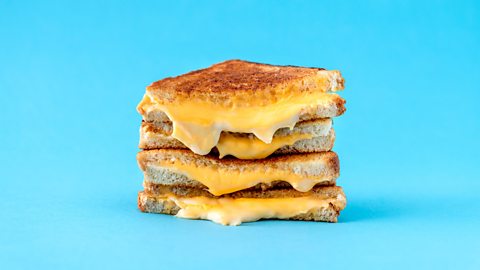 four halves (two sandwiches worth) of cheese toasties on top of each other with gooey cheese coming out of the middle 