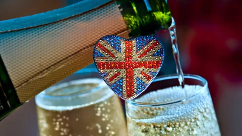 Alamy A bottle pouring out champagne into two glasses, with a heart-shaped Union Jack flag in the centre of the frame (Credit: Alamy)