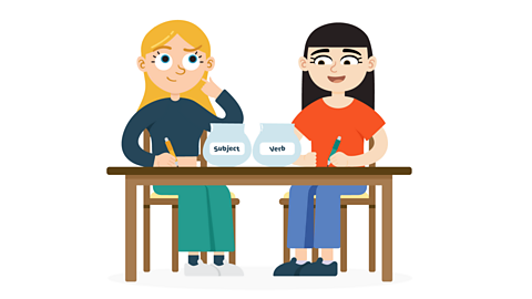 Two girls sitting at a table writing. There are 2 bowls on the table with labels, which say ‘subject’ and ‘verb’.