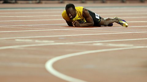 Jamaican sprinter Usian Bolt lies on his stomach on the running track, a grimace on his face.