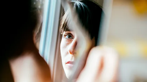 Getty Images The partial reflection of a woman's face in a mirror (Credit: Getty Images)