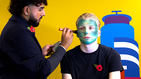 Glow Up MUA Rahual Das creating a reptilian AI-inspired Halloween look on a model.