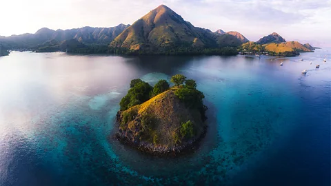 Alamy The Komodo Islands are shown from above, with a smaller island in the foreground surrounded by deep blue ocean and an island with a taller peak in the background (Credit: Alamy)