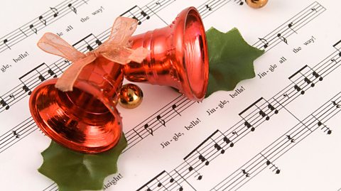A pair of bells atop a music sheet with the song Jingle Bells written on