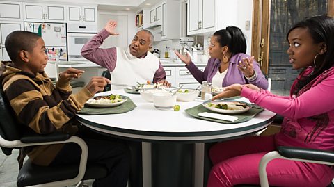 Family argument at dinner table - Mum and daughter react as father is angry with cheeky son