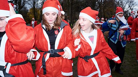 Three young women dressed as Father Christmas join others for a charity run in a park