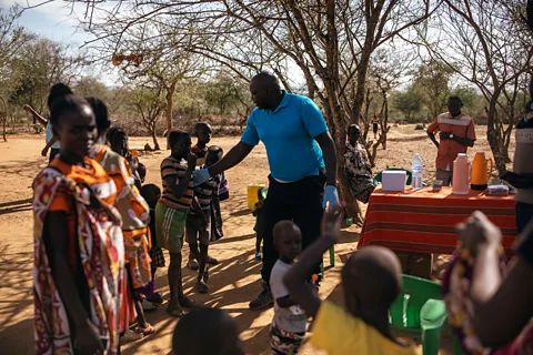 Kang-Chun Cheng Andrew Ochieng examines villagers beside his makeshift visceral leishmaniasis clinic in the shade of a tree in Akorikeya (Credit: Kang-Chun Cheng)