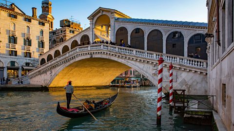 A man on his Gondola boat on Canal Grande in front of Rialto Bridge in Venice, Italy on a sunny day