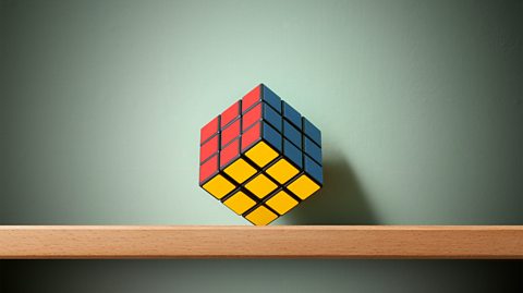 A solved Rubik's cube on a shelf