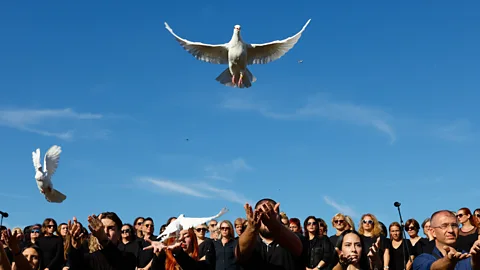 Marko Drobnjakovic/ Associated Press Two doves flying above a crowd of people in Serbia (Credit: Marko Drobnjakovic/ Associated Press)