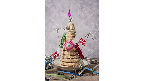 A lavishly decorated Danish kransekage cake complete with crackers, feathers and danish flags