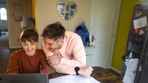 Dad and son share a joke over some online content they're viewing