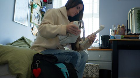 Home educated teenager Mali putting away her ice skates in her bedroom