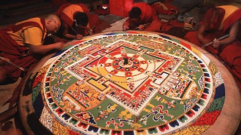  Tibetan Buddhist monks with a sand mandala resembling the Wheel of Life, a diagram that shows the cycle of life and karma. 