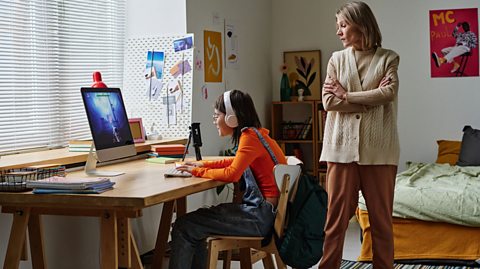 Parent looks over the shoulder of child who is online gaming