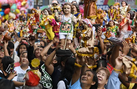 Getty Images People in Manila holding figurines of the Santo Nino (Child Jesus) – an icon introduced to the Philippines by Magellan (Credit: Getty Images)