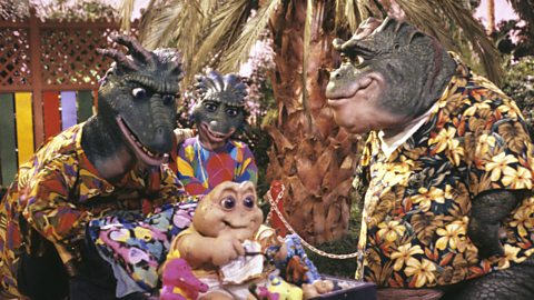 A still from the tv show Dinosaur, with the Sinclair family in Hawaiian shirts, by a palm tree