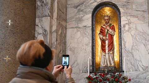 A woman takes a photo of the statue of Saint Valentine at Whitefriar Street Church in Dublin, Ireland