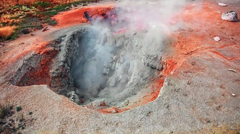 Gas coming from a large hot spring, orange coloured rock surrounding the area