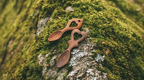 Traditional carved Welsh love spoons on a mossy rock background