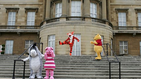 Tigger kicking out a leg mid-bounce with Pooh watching on the steps of the gardens of Buckingham Palace, with Eeyore and Piglet at the bottom of the stairs